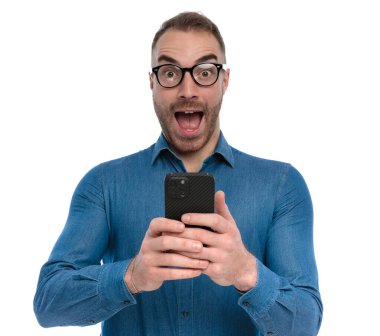 excited casual guy with glasses getting an email with great news, being surprised and posing on white background in studio