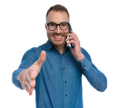 happy casual man with glasses talking on the phone and shaking hand, smiling and posing on white background in studio