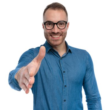 portrait of attractive guy with glasses smiling and shaking hand in front of white background in studio