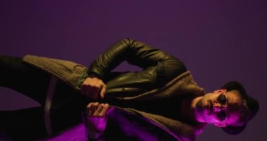 cool fashion man arranging and pulling leather jacket, looking to side and rubbing palms, fixing hat and walking away