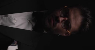 close up video of handsome young groom with round glasses standing in the spotlight and looking to side
