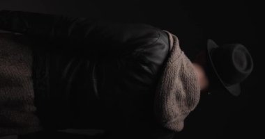 back view of young man arranging glasses, smiling and pointing hand to the camera while being in the spotlight