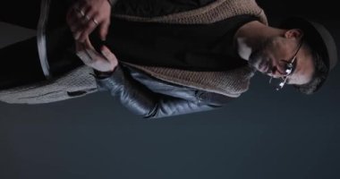 sexy young man rubbing palms, looking to side and arranging leather jacket, being confident and walking away