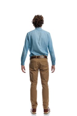 Full body picture of handsome casual man turning his back at the camera, standing, wearing eyeglasses against white studio background