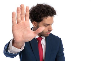 elegant young businessman in suit holding hand up and showing palm as enough gesture in front of white background in studio
