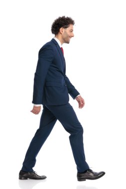 side view of curly hair man being happy, smiling and walking in front of white background in studio