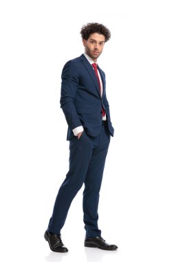 full body picture of sexy businessman holding hands in pockets and posing in front of white background in studio