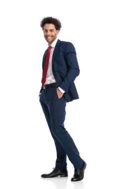 full body picture of happy young businessman posing with hands in pockets and smiling in front of white background in studio