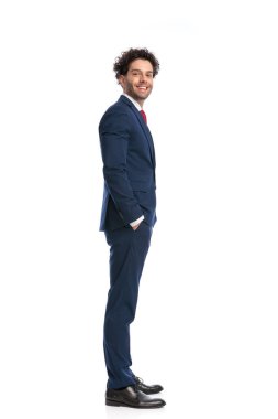 side view of happy elegant businessman smiling and posing with hands in pockets in front of white background in studio