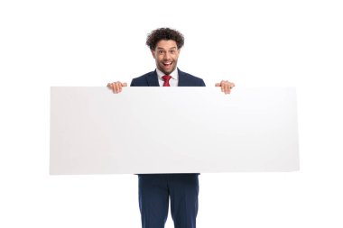 excited young businessman holding and presenting white empty board and smiling in front of white background