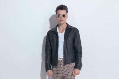 Portrait of  handsome casual man posing with masculine vibe, standing, wearing sunglasses in a fashion pose