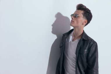 Portrait of  handsome casual man looking up and posing with style, standing, wearing sunglasses in a fashion pose