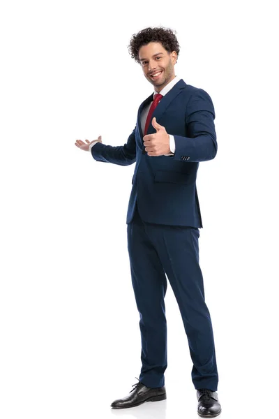 スーツ姿の魅力的なビジネスマンがスタジオで白い背景の前で親指を立て笑顔でポーズをとる — ストック写真