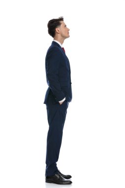 attractive businessman feeling annoyed to wait with hands in pockets, wearing a suit and tie against white background