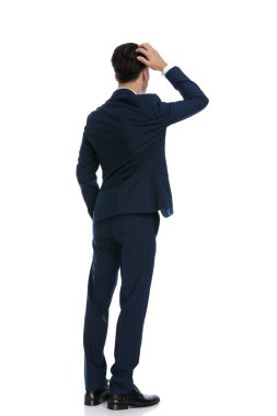 elegant businessman scratching his head and feeling confused, wearing a suit and tie against white background
