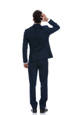 attractive businessman scratching head and pondering, wearing a suit and tie against white background