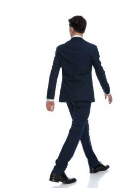 handsome businessman walking one way and looking the other, wearing a suit and tie against white background