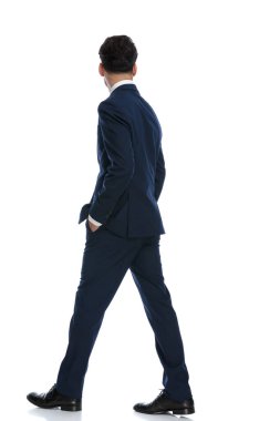 elegant businessman walking and being distracted by something, wearing a suit and tie against white background