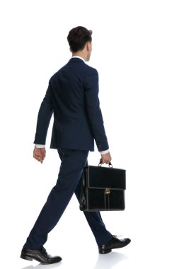 young businessman walking and holding a briefcase, wearing a suit and tie against white background