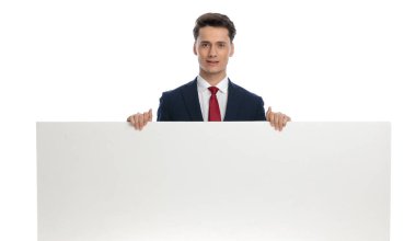 attractive businessman presenting his landscape billboard, wearing a suit and tie against white background