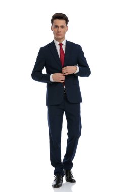 handsome businessman fixing his jacket and looking at camera, wearing a suit and tie against white background