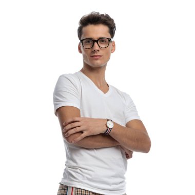 proud young man with glasses crossing arms, smiling and being confident while posing in front of white background in studio