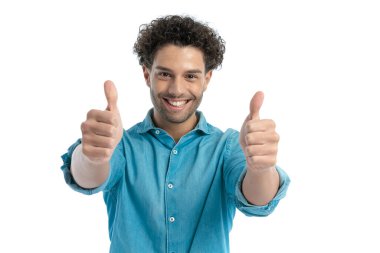 proud casual man in denim shirt making thumbs up gesture and smiling in front of white background in studio