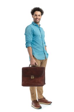 lebanese man holding suitcase and smiling while standing with hand in pocket in front of white background in studio