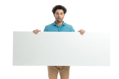 shocked casual man with curly hair presenting white board and being surprised in front of white background