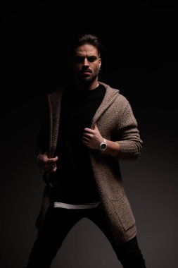 Portrait of handsome casual man arranging his coat with tough attitude, standing, in a fashion pose