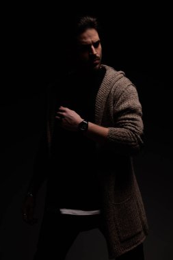 Portrait of young casual man looking away from the dark, standing, in a fashion pose