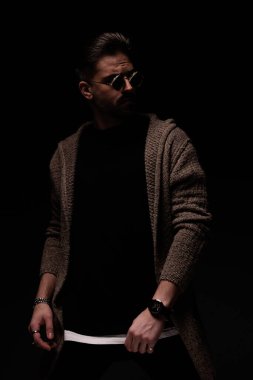 Portrait of attractive male model looking over his shoulder, standing, in a fashion pose