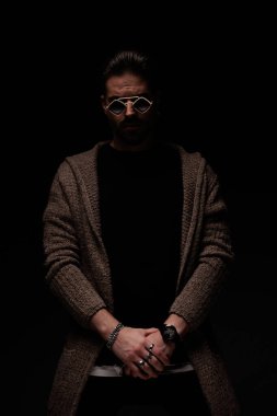 Portrait of young man holding hands together with a tough stance, standing, in a fashion pose