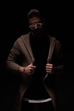 Portrait of young guy pulling his coat with cool syle, standing, in a fashion pose