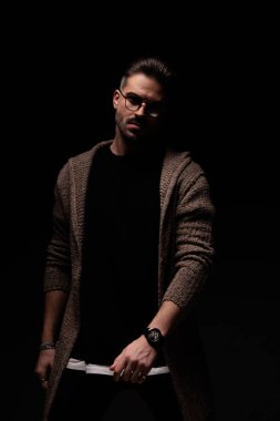 Portrait of attractive casual man posing from the shadows, standing, in a fashion pose