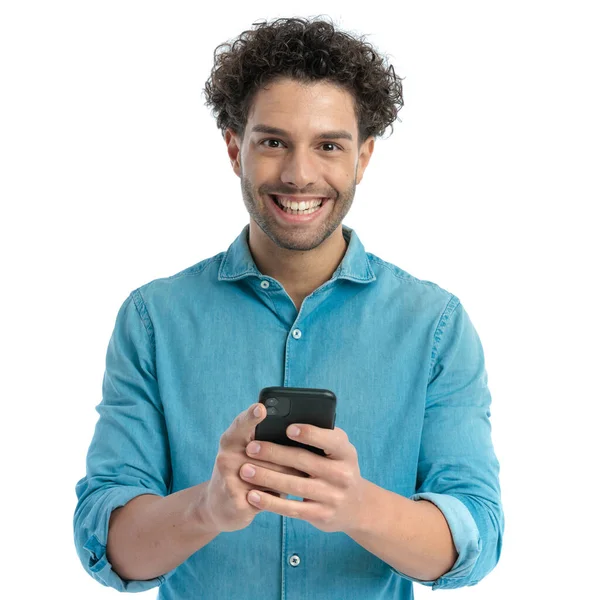 Podekscytowany Człowiek Kręconymi Włosami Trzymając Telefon Pisząc Mail Przed Białym — Zdjęcie stockowe