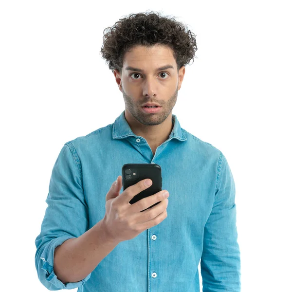 Portrait Surprised Young Man Denim Shirt Holding Telephone Reading News — Zdjęcie stockowe