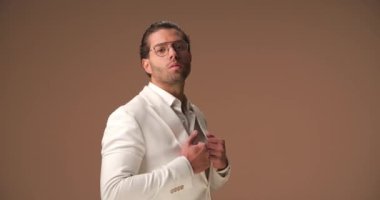 sexy tough businessman arranging his suit, turning around, rubbing palms and pointing at camera