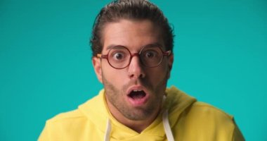 casual man coming closer and feeling shocked, slapping his face, puffing cheeks