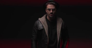 mysterious young man with hat and glasses being confident and looking to side while police lights are on