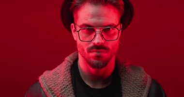 dangerous man with hat and glasses being serious while police lights are on and camera is zooming out