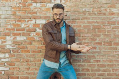 Çekici sıradan bir adamın portresi avuçlarını sert bir titreşimle ovuyor, eski bir ortaçağ kasabasında gözlük ve deri ceket giyiyor.