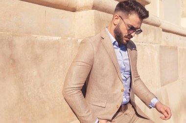 Eski bir ortaçağ kasabasında, duvara yaslanmış ve güneş gözlüğü takmış seksi iş adamının portresi.