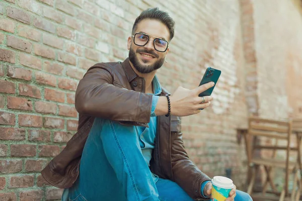 Yakışıklı Sıradan Bir Adamın Portresi Telefonuyla Içkisiyle Eğleniyor Eski Bir — Stok fotoğraf