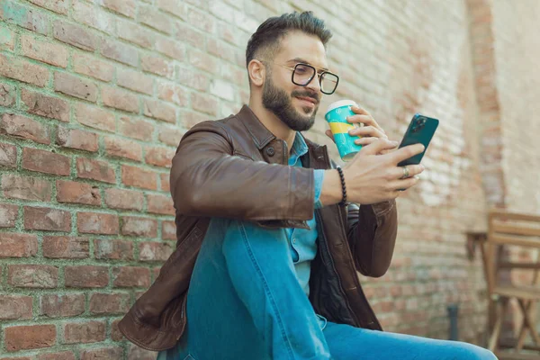 Retrato Atractivo Hombre Casual Disfrutando Teléfono Bebida Usando Anteojos Chaqueta —  Fotos de Stock