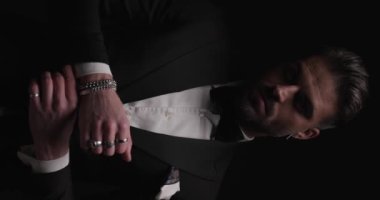 İş adamı bileziği tamir ediyor, kollarını sıvayıp dramatik bir şekilde kameraya bakıyor.