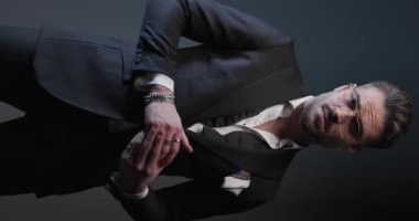 Yakışıklı iş adamı yüzüklerini ve ceketini tamir ediyor, parmaklarını ovuyor ve sert enerjiyle etrafa bakıyor.