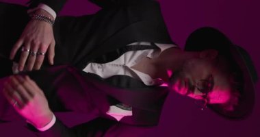 Genç, seksi iş adamı smokinini ayarlıyor, ellerini cebine sokuyor, sert tavırlarıyla etrafa bakıyor.