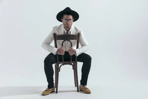 Elegancki Człowiek Moda Kapeluszu Okulary Trzymając Krzesło Tyłu Siedzi Szarym — Zdjęcie stockowe