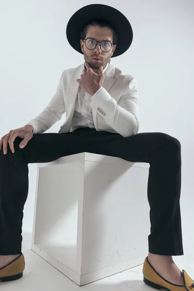 Высокомерный Человек Моды Шляпе Трогательный Подбородок Думать Сидя Сером Фоне — стоковое фото
